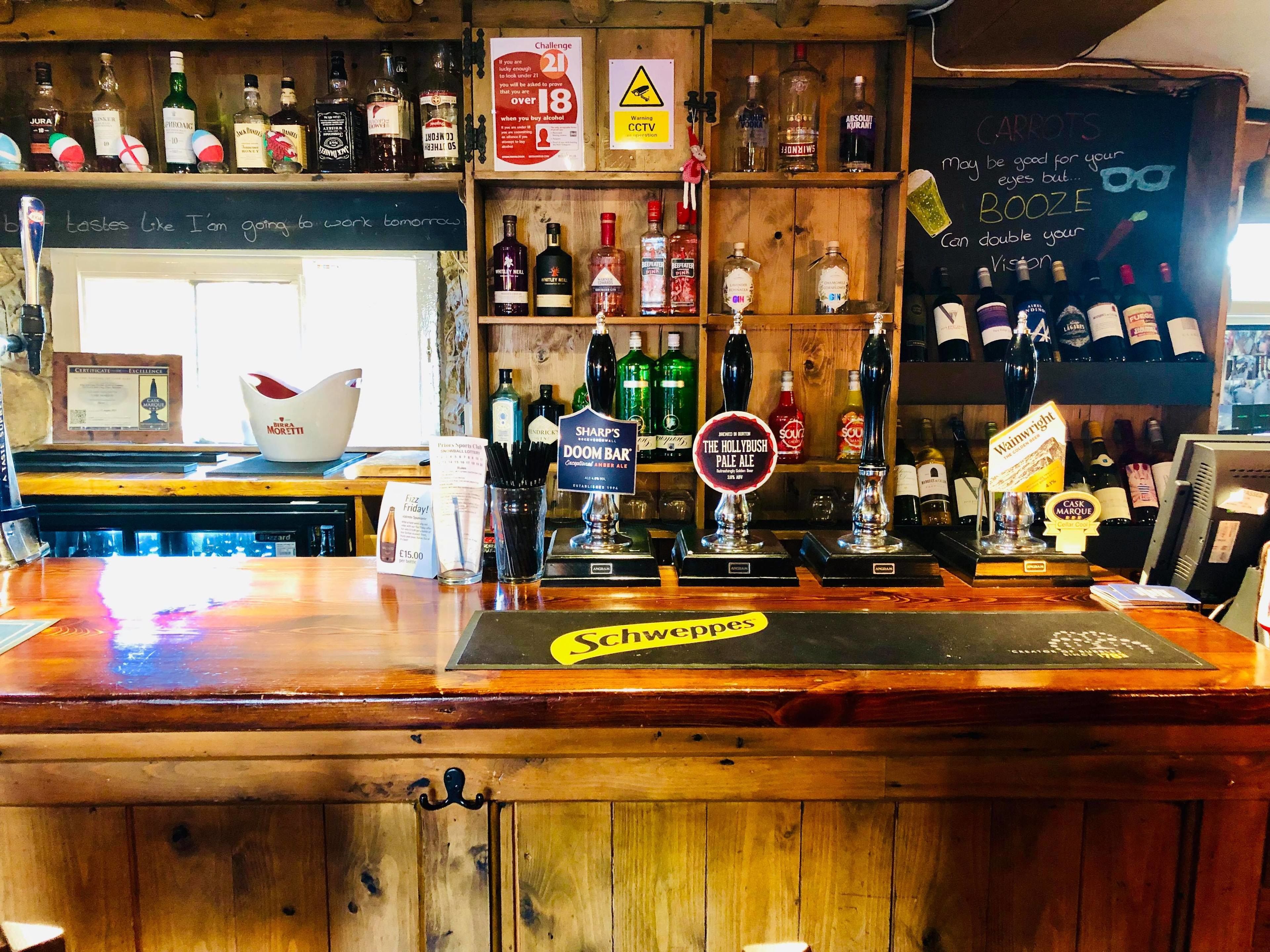 A bar with a variety of liquor bottles, a chalkboard menu, and a sign indicating a challenge for under 21 customers.