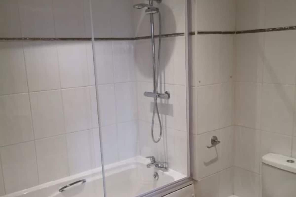 A bathroom with a glass-enclosed shower, a white toilet, and a sink.