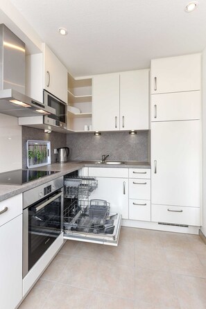 A modern kitchen with white cabinets, stainless steel appliances, and a built-in dishwasher.