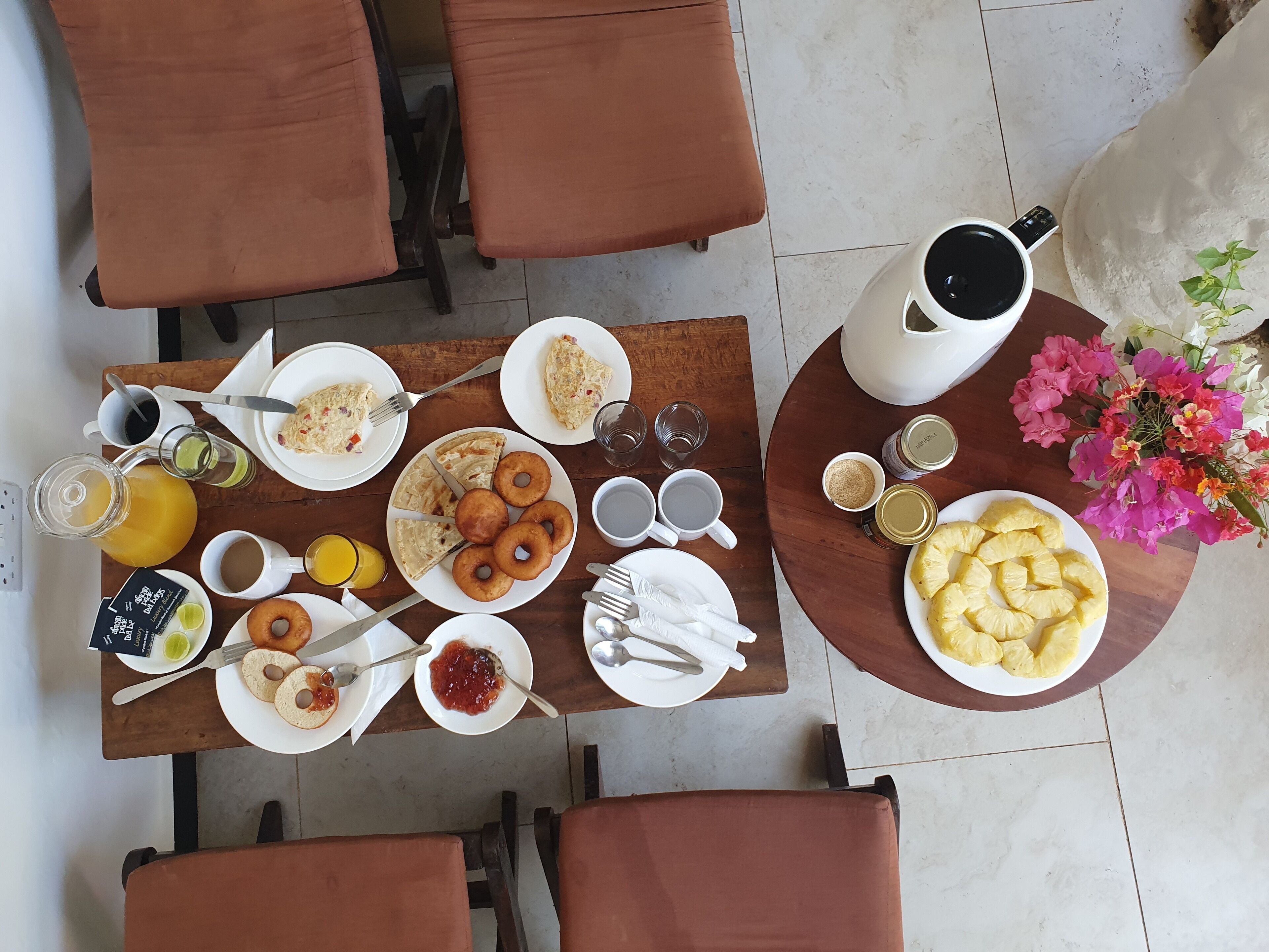 A breakfast table with plates of food, drinks, and a coffee maker.