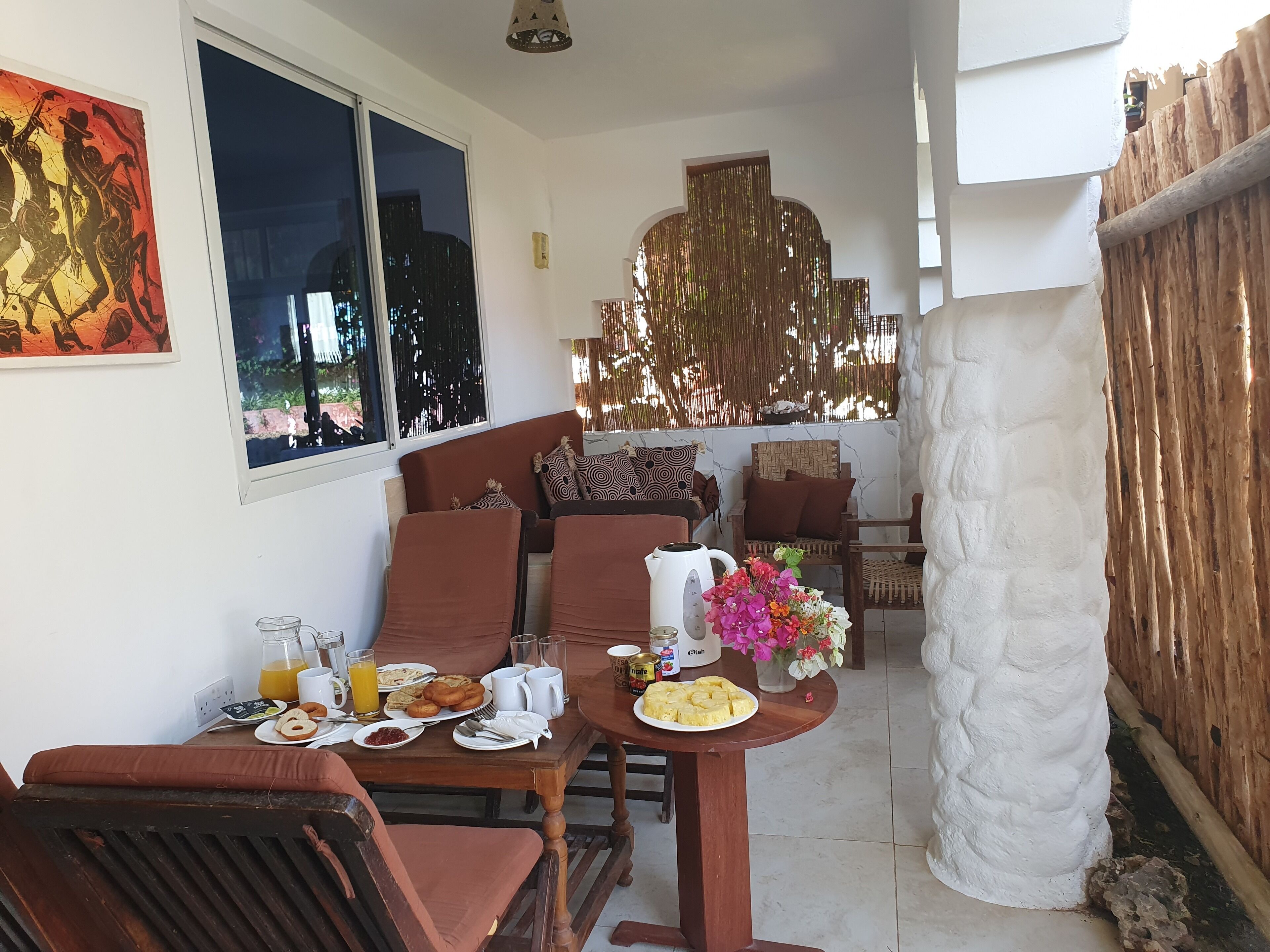 A dining area with a table set for breakfast, including plates of food, drinks, and a vase of flowers.