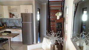 Eine moderne Küche mit einem Edelstahl-Kühlschrank, einem Esstisch mit Stühlen und einem weißen Sofa im Wohnbereich.
