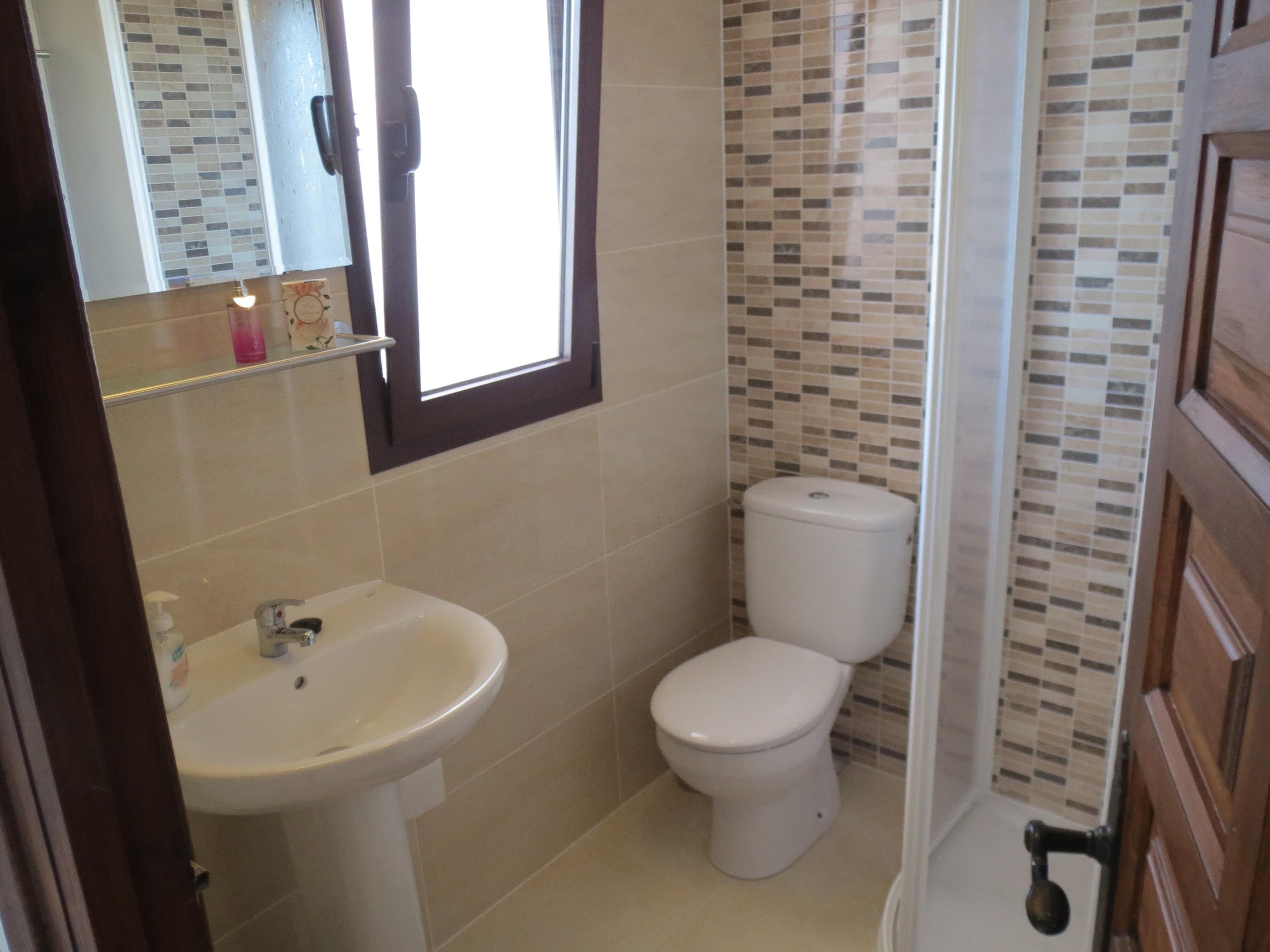 A bathroom with a white sink, toilet, and a window.