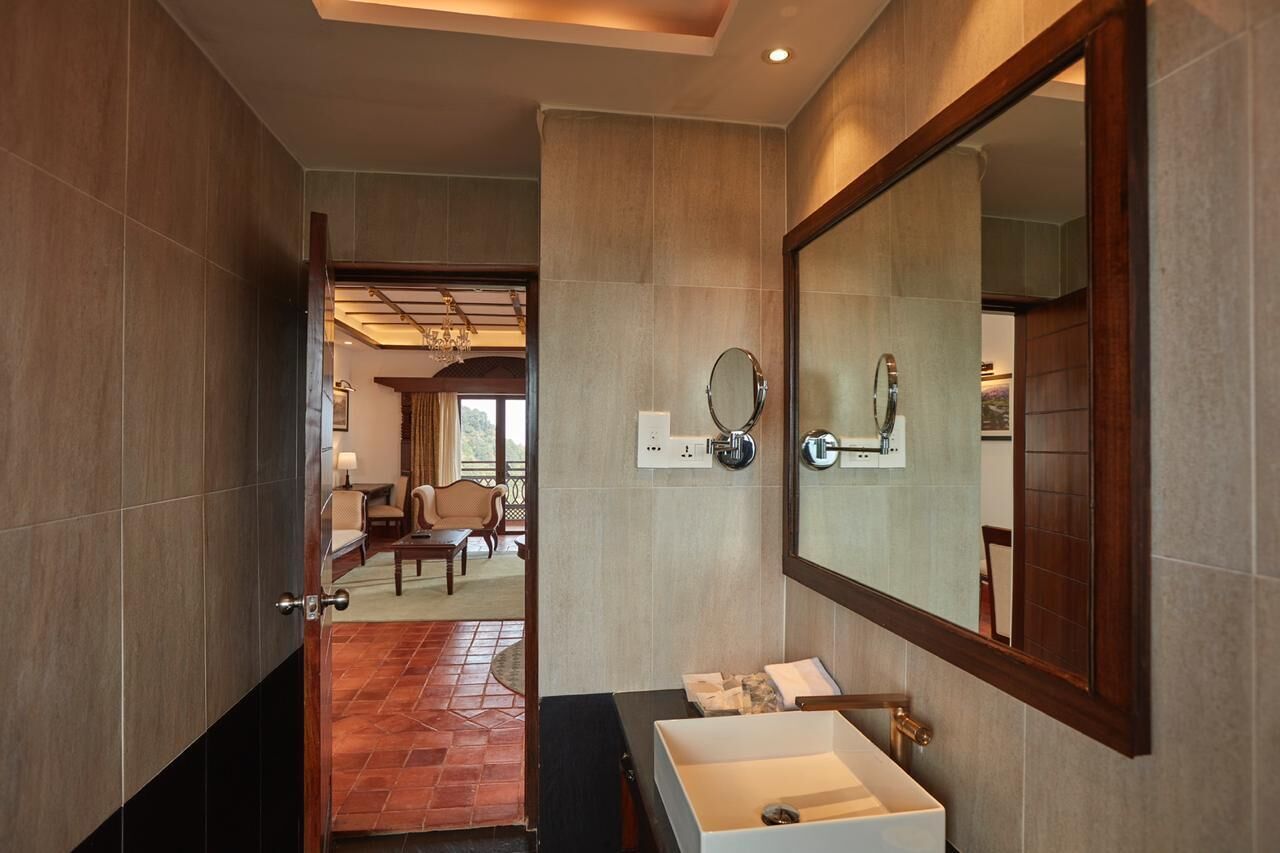 Un bagno moderno con un grande specchio, un lavandino bianco e vista su un soggiorno con camino.