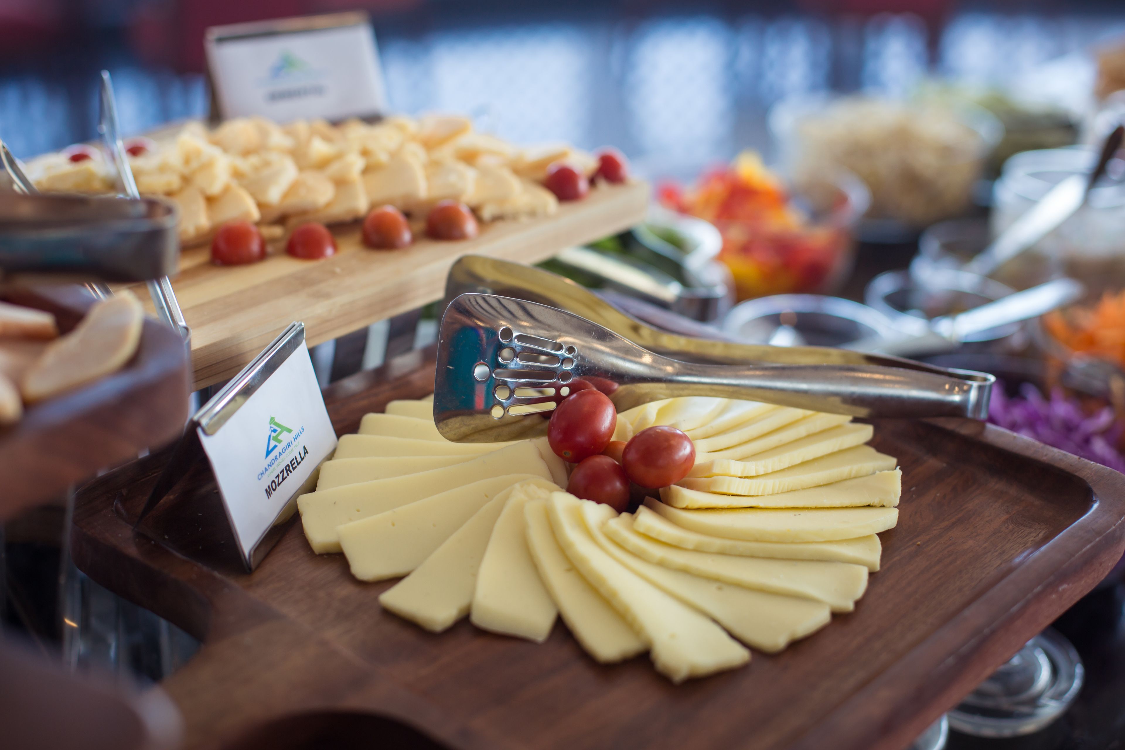 A buffet with various food items including cheese, fruits, and a sign for 'NOZZRELLA'.