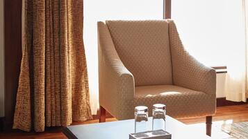Una habitación con un ventanal grande, una silla y una mesa con dos recipientes de vidrio.