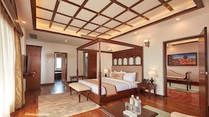 Un dormitorio espacioso con cama con dosel, suelo de madera y un ventanal grande.