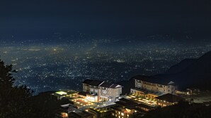 Un hotel con varias dependencias, una zona de estacionamiento y vistas a un paisaje urbano nocturno.