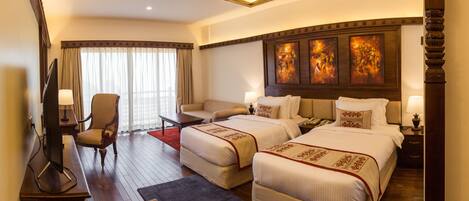 Quarto de hotel com duas camas, uma escrivaninha, uma cadeira e uma televisão.