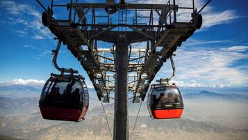 Sistema de teleférico con dos cabinas suspendidas de una torre central, con vistas a un paisaje montañoso.