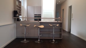 A modern kitchen with a bar area featuring three stools.
