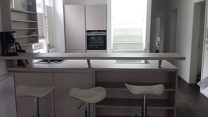 A modern kitchen with a central island, bar stools, and built-in appliances.