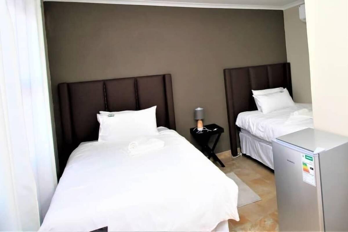 Una habitación de hotel con dos camas, un escritorio pequeño y un refrigerador.