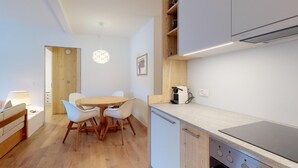A modern kitchen with a round dining table, white chairs, and a built-in stove.