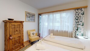 A hotel room with two beds, a wooden cabinet, a chair, and a painting on the wall.