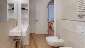 A modern bathroom with a glass-enclosed shower, a white sink, and a bidet.