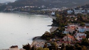 Une ville côtière avec des bâtiments qui bordent la plage, une vue dégagée sur la mer et un paysage vallonné en arrière-plan.