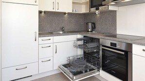 A modern kitchen with white cabinets, a built-in microwave, an oven, and a dishwasher.