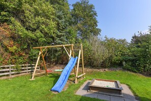 Une aire de jeux avec une balançoire en bois et un toboggan bleu.