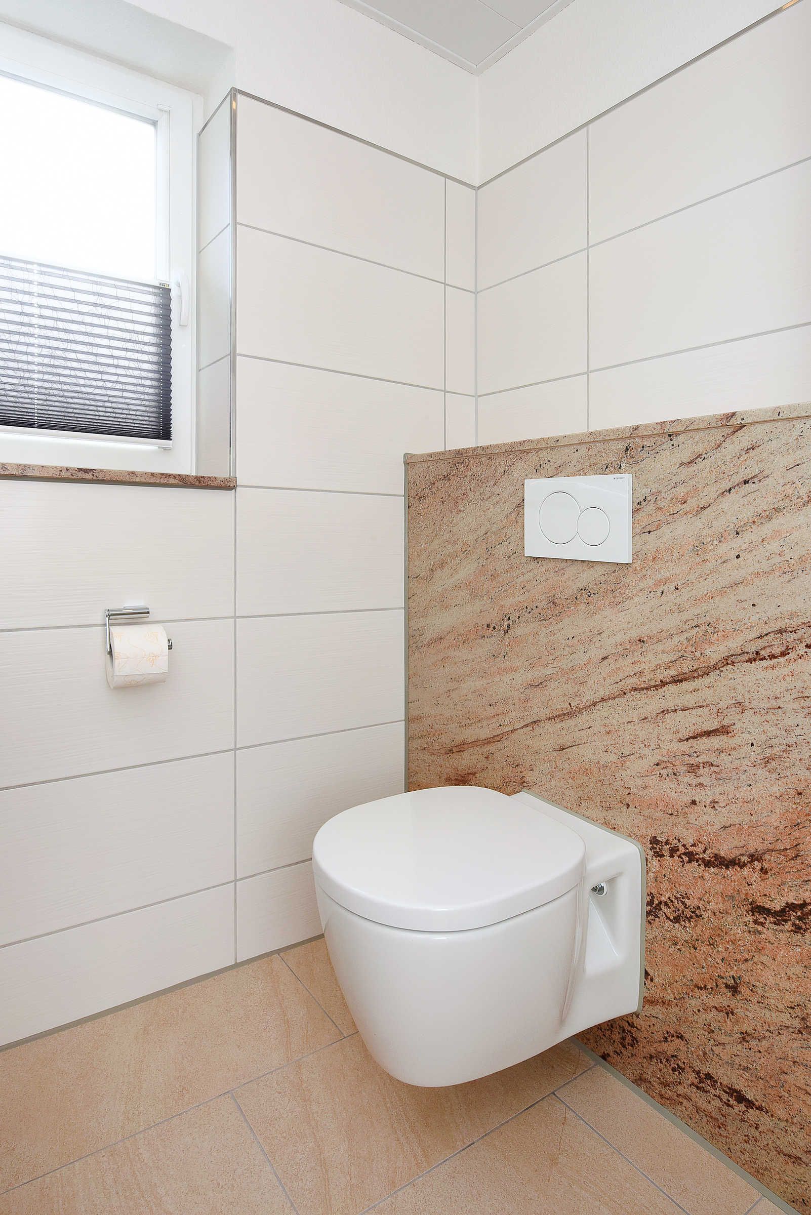 A modern bathroom with a white toilet, beige tiles, and a marble accent wall.