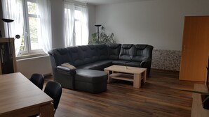 A living room with a sectional sofa, a wooden coffee table, and a dining table. - Apartment in Fürstenwalde (Fürstenwalde/Spree)