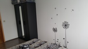 A bedroom with a bed, a wardrobe, and wall art of flowers. - Apartment in Fürstenwalde (Fürstenwalde/Spree)