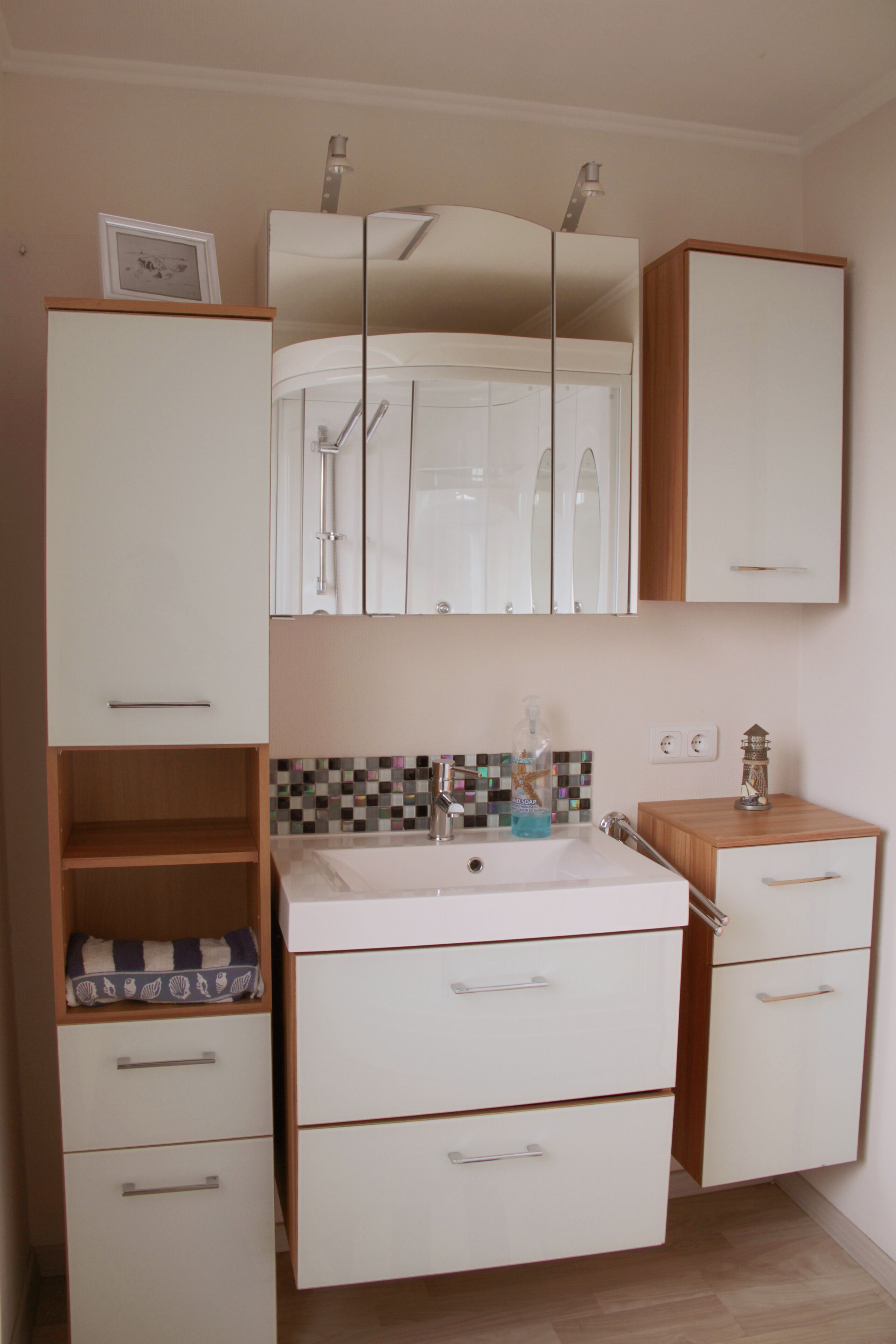 Une salle de bain avec un lavabo blanc, un miroir et des armoires.