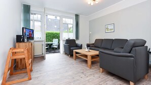 Un salon moderne avec un canapé, des fauteuils, une table basse et un téléviseur posé sur un meuble.