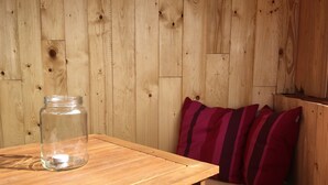 Une table en bois, un bocal en verre et un coussin à rayures.