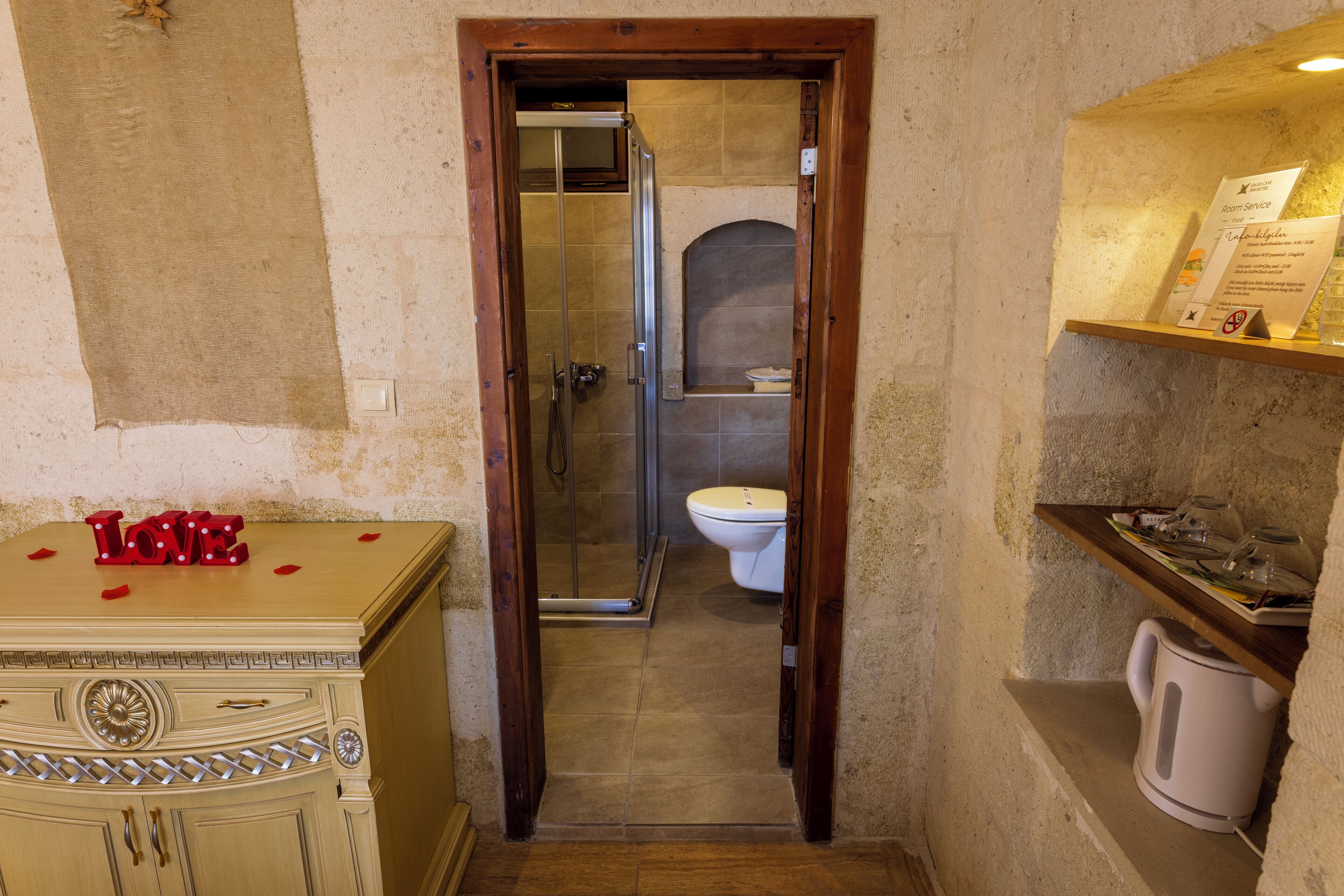 Un pasillo estrecho que conduce a un baño con ducha, inodoro y tocador con espejo.