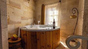 Un baño con una bañera de madera, un lavamanos blanco y un frutero.