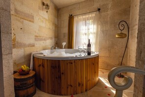 A bathroom with a wooden bathtub, a white sink, and a fruit bowl. - Eagle Cave Inn (Ürgüp)