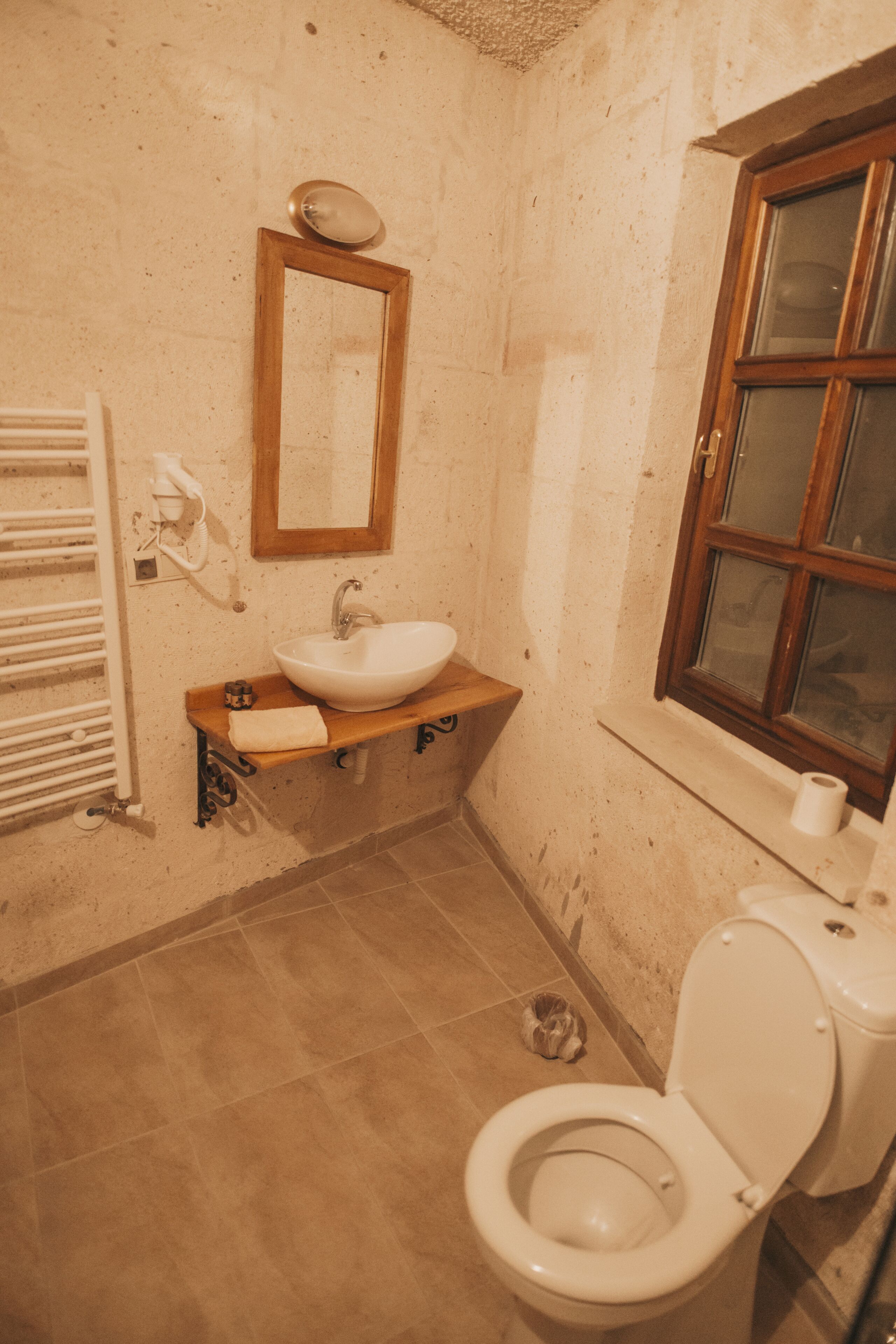 Un baño pequeño con un lavamanos blanco, un espejo, una ventana y un inodoro.