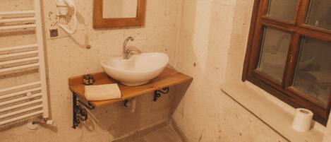 Un baño pequeño con un lavamanos blanco, un espejo, una ventana y un inodoro.