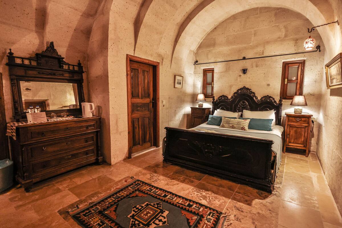 A bedroom with a large bed, a dresser, a mirror, and a chandelier.