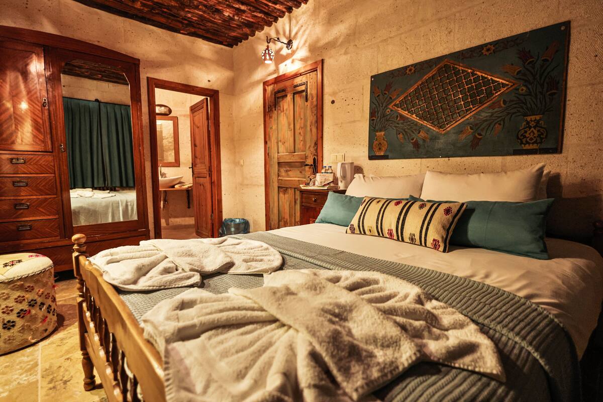 A cozy bedroom with a wooden bed, a large mirror, and a decorative wall piece.