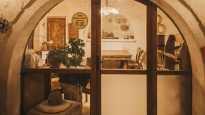 Un arco de entrada a una habitación con una mesa de madera y sillas, una planta en maceta y varios objetos en estantes.