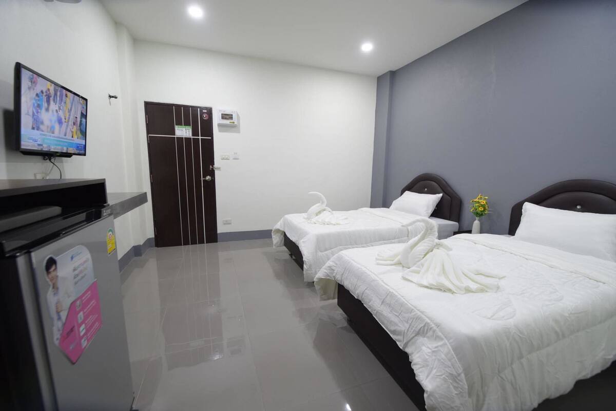 Habitación de hotel con dos camas, televisión, minibar y una puerta con cerradura.