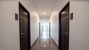 Un pasillo largo y estrecho con puertas a ambos lados, que conduce a una habitación luminosa al final.
