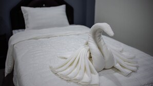 Una cama bien hecha con una toalla dispuesta en forma de cisne.