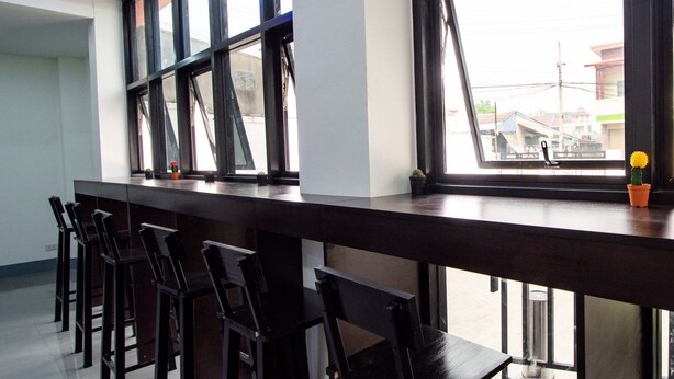Una zona de bar con una barra alargada y varias sillas.