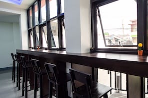 Una zona de bar con una barra alargada y varias sillas.