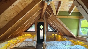 A cozy attic bedroom with two beds, wooden beams, a skylight, and a green wall. - Vacation in the Ore Mountains (Sehmatal-Cranzahl)
