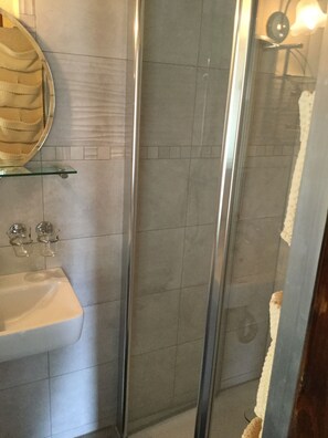 Une salle de bain avec une douche à parois de verre, un lavabo blanc et un miroir au-dessus du lavabo.