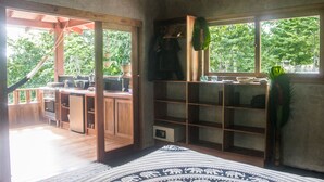 Un'ampia stanza con un'ampia finestra, un angolo cottura con mobili in legno e una zona relax con un tappeto decorato.