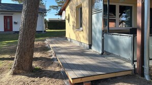 A house with a wooden deck, a satellite dish, and a window. - Vacation home close to nature with fireplace and rowing boat on Lake Plau - House 26 (Plau am See OT Quetzin)