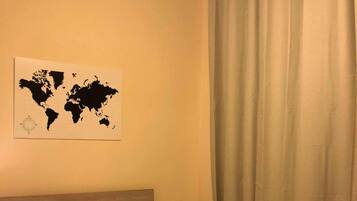 A hotel room with a bed, a world map on the wall, and a curtain.