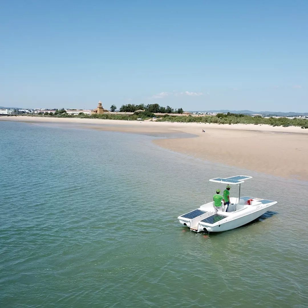 A boat with solar panels docked near a beach.