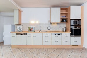 A modern kitchen with white cabinets, a stainless steel oven, and a coffee maker.
