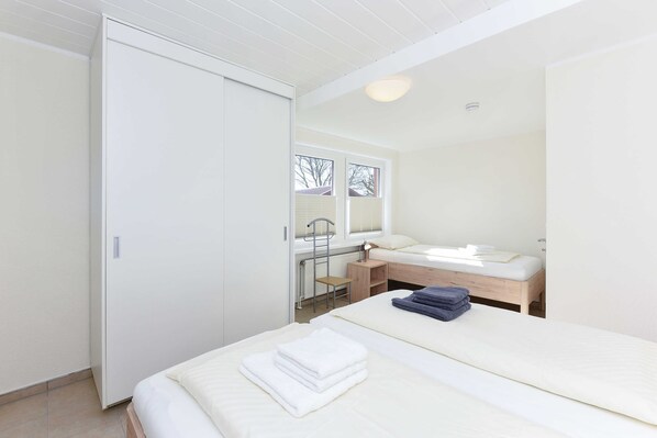 A bedroom with a bed, a desk, and a window.